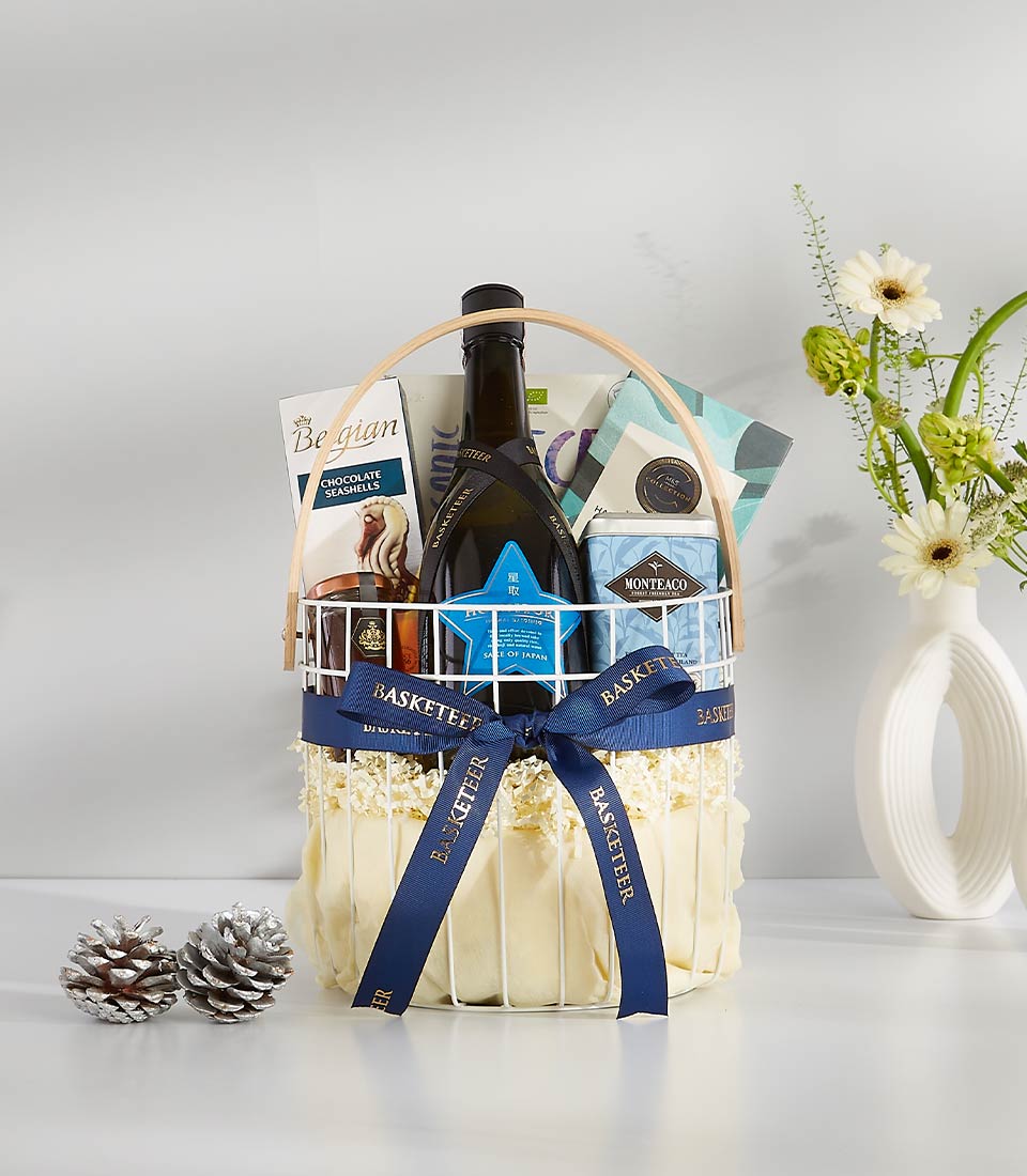Luxury wine gift basket with red wine, gourmet chocolates, and premium treats in white wire design with blue ribbon