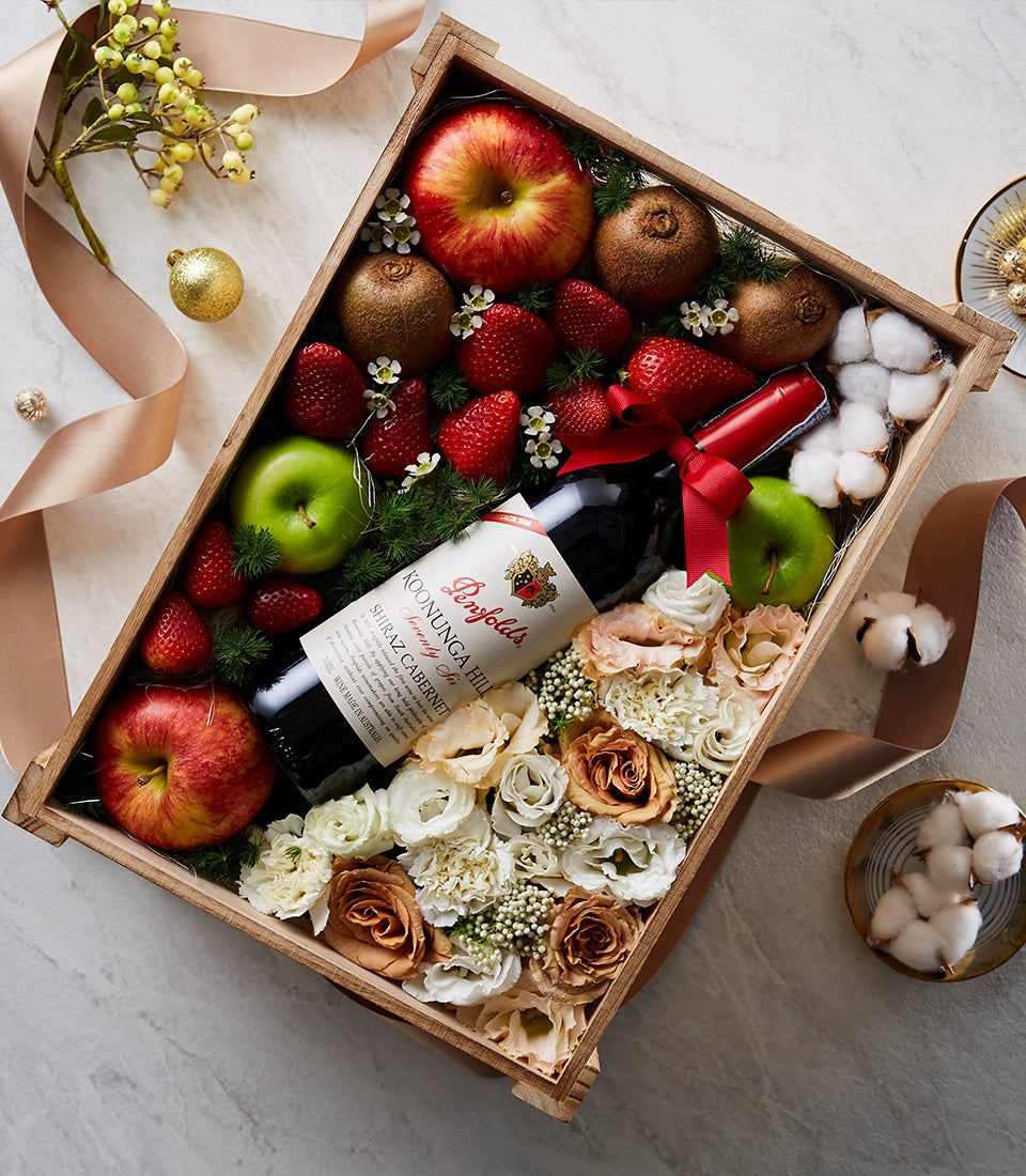 Penfolds red wine with fresh fruit, strawberries, kiwis, and white flowers in wooden gift crate