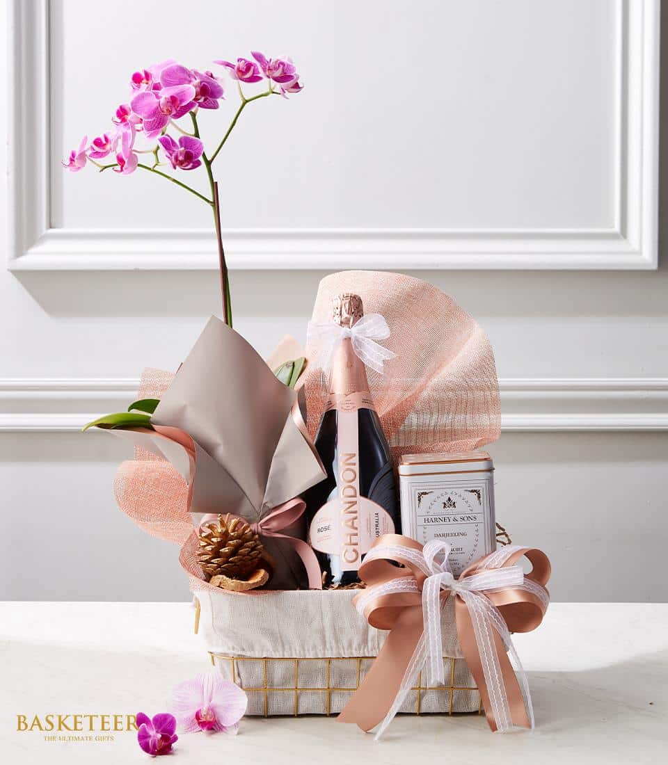 Luxe rosé champagne gift basket with pink orchid plant, Darjeeling tea, and satin ribbon bow