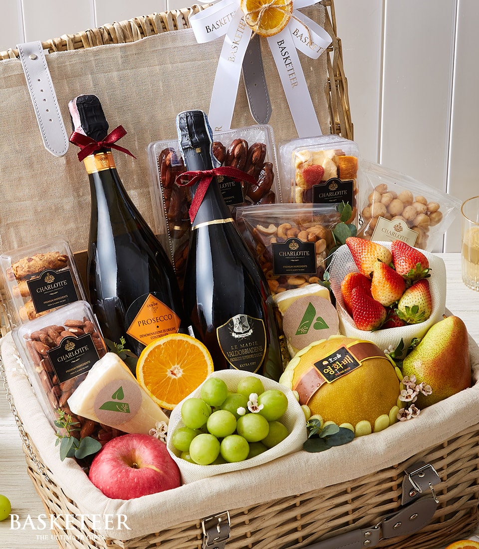 Luxury wicker hamper with twin sparkling wine bottles, fresh fruit, gourmet nuts, cheese and artisan treats
