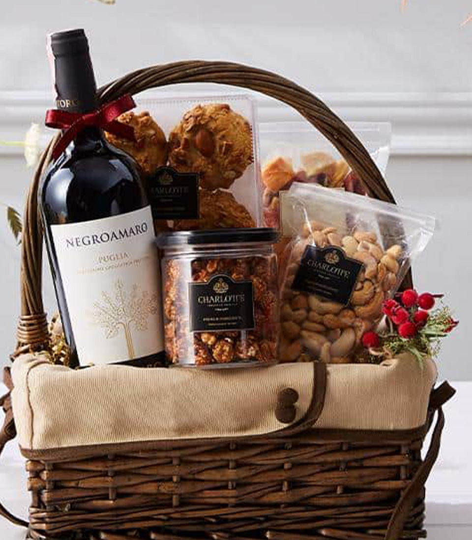 Premium wine gift basket with Negroamaro red wine, artisan cookies, caramel popcorn, and cashews in woven wicker