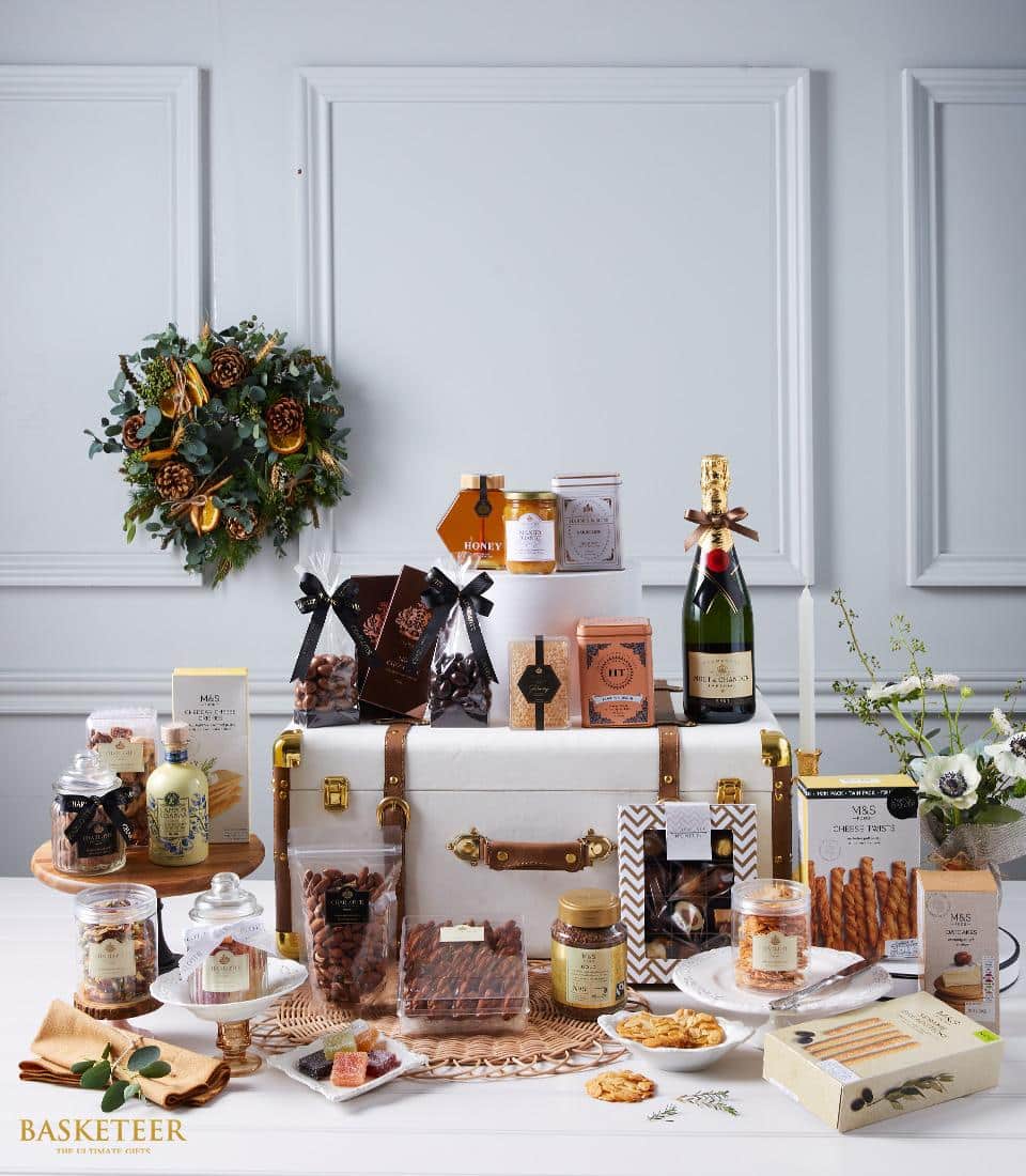 Grand luxury hamper with champagne, gourmet chocolates, honey, and nuts in white leather trunk with gold accents