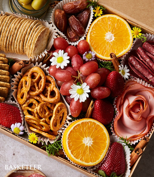 Artisan charcuterie snack box with cured meats, cheeses, crackers, fresh fruits and dried dates in luxury gift hamper