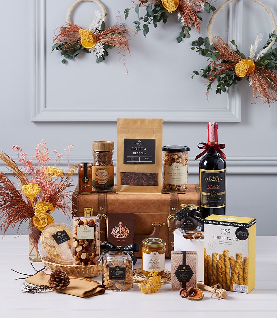 Luxury wine gourmet hamper with red wine, artisan chocolates, nuts, honey, and gourmet spreads in leather trunk