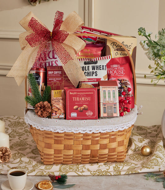 Woven wicker gift basket with premium drip coffee, chocolate, almond milk, and gourmet snacks tied with red burlap ribbon
