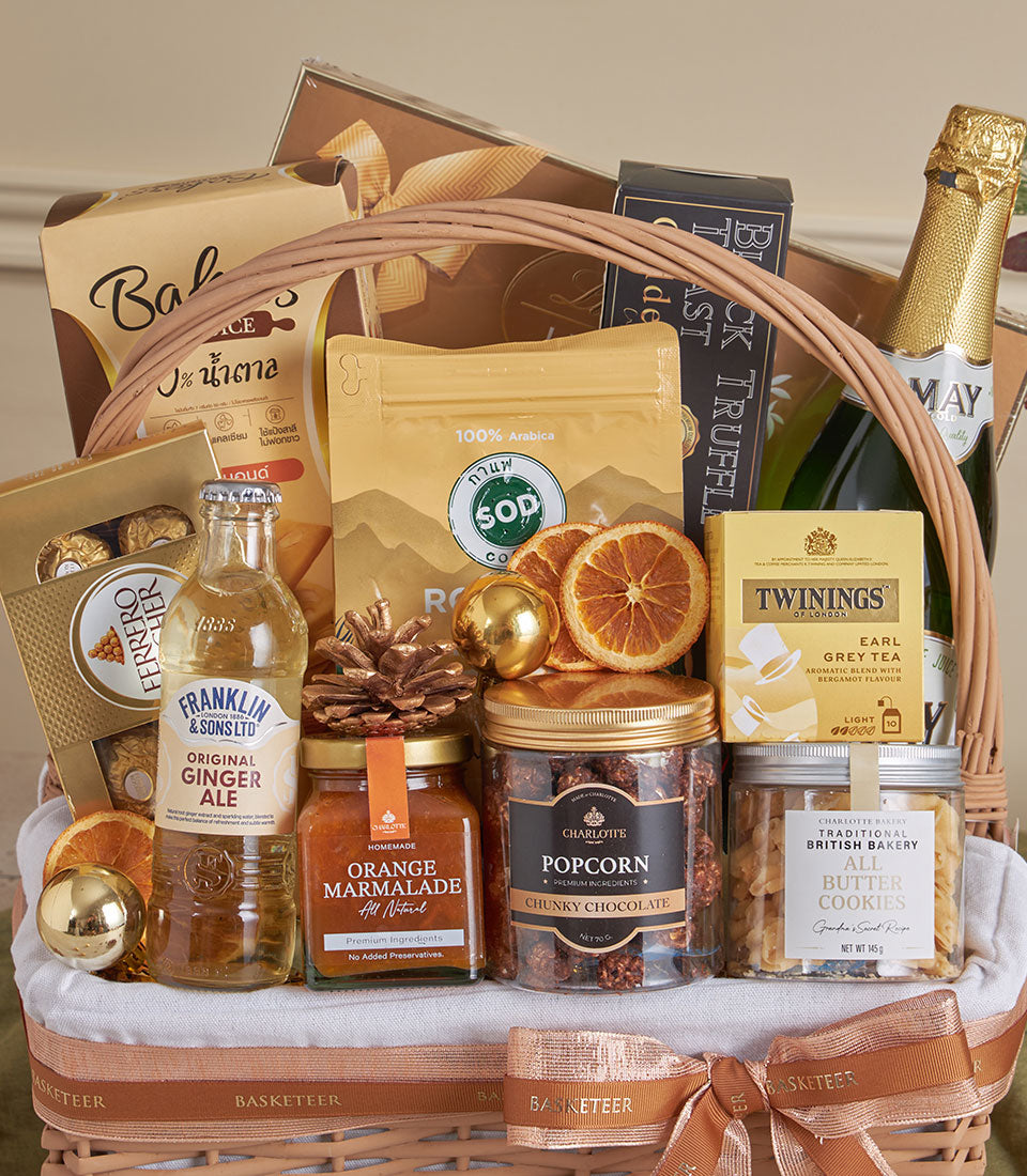 Wicker gourmet gift basket with champagne, truffle, coffee, tea, chocolates, and artisan treats tied with copper ribbon for