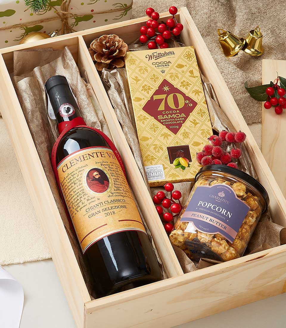 Premium wine and dark chocolate gift box with gourmet popcorn, festive red berries and gold accents