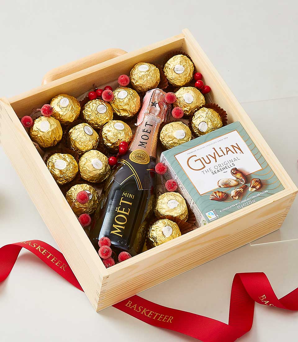 Premium wine and chocolate gift box with Ferrero truffles, champagne, and frosted berries in wooden crate