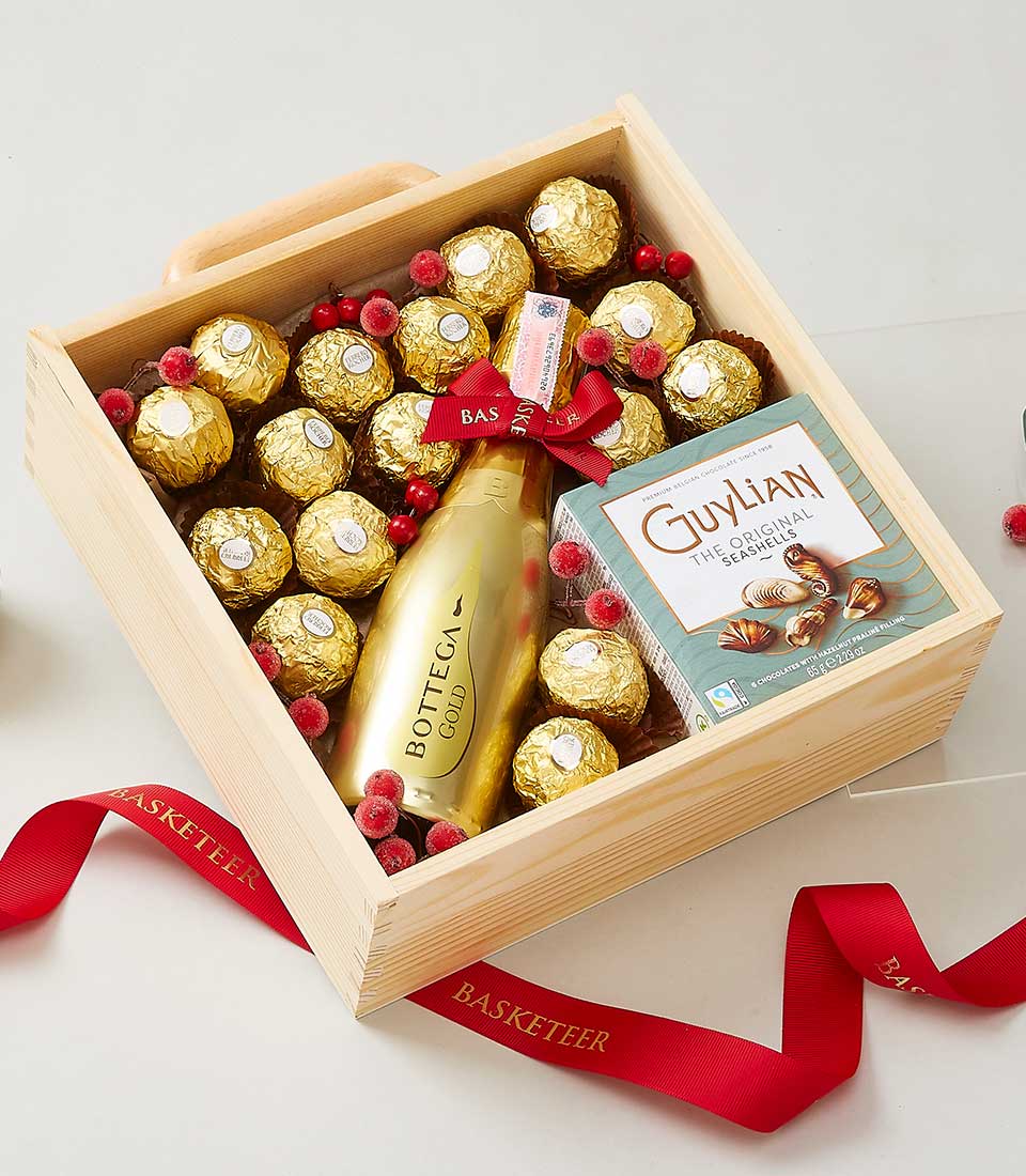 Luxury wooden gift box with gold sparkling wine, Ferrero Rocher chocolates, and frosted berries