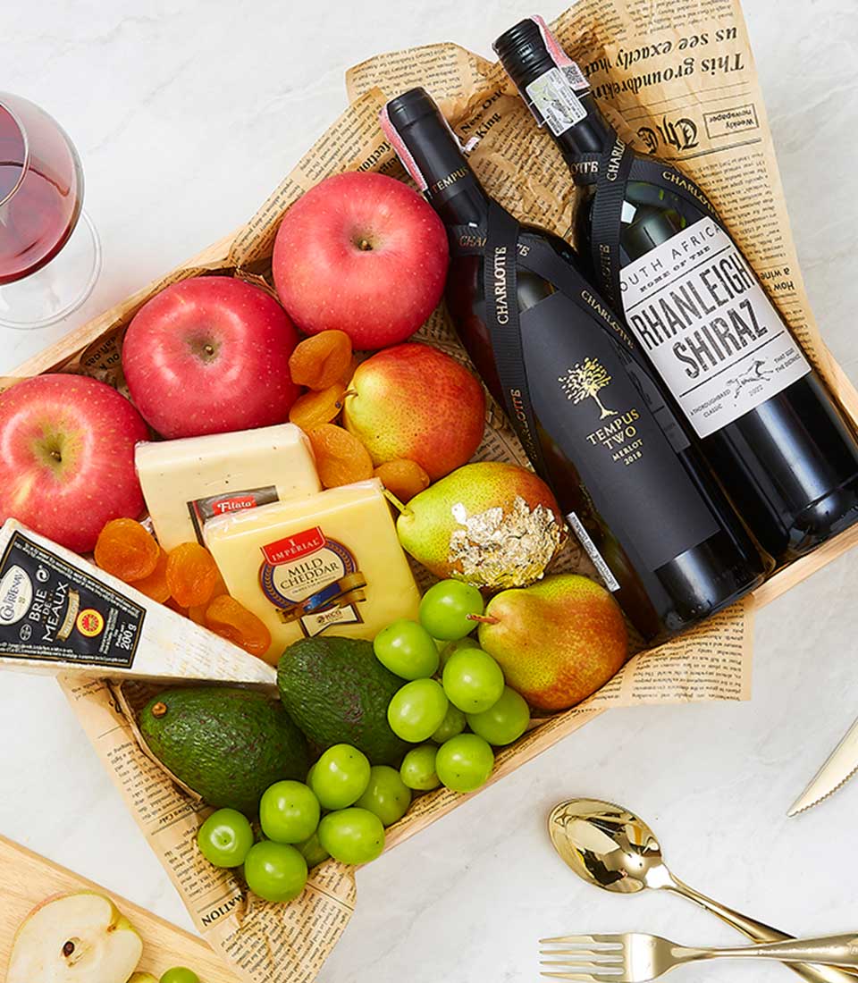 Premium wine and cheese gourmet hamper with red wine, cheddar, brie, fresh fruit in wooden basket