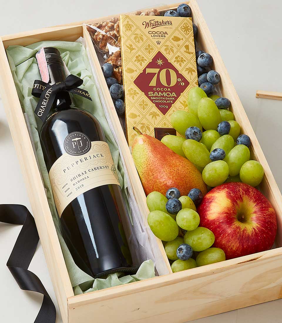Red wine and dark chocolate gourmet gift hamper with fresh fruit and walnuts in wooden box