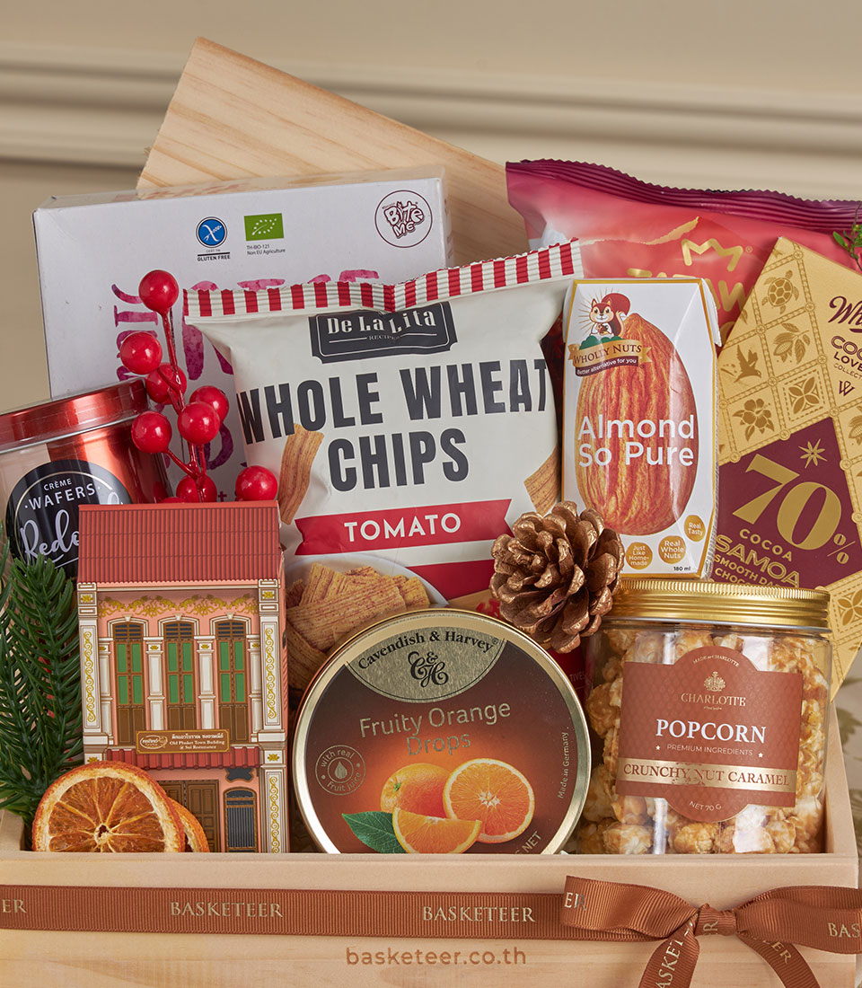 Wooden gift basket with healthy snacks, dark chocolate, almond milk, and caramel popcorn for New Year
