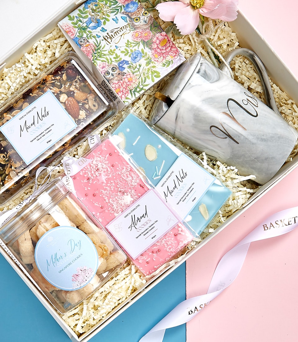 Mother's Day gift box with marble mug, notebook, gourmet cookies, and mixed nuts on pink and blue background