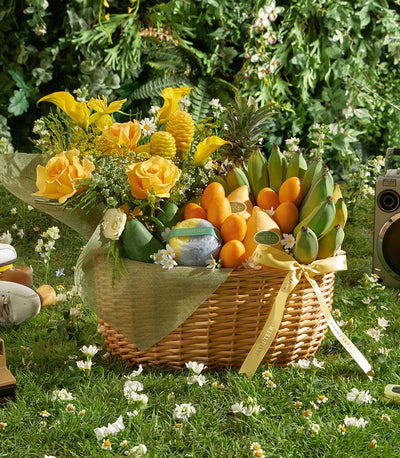 Golden tropical fruit and flower gift basket with roses, mangoes, and pineapple on wicker