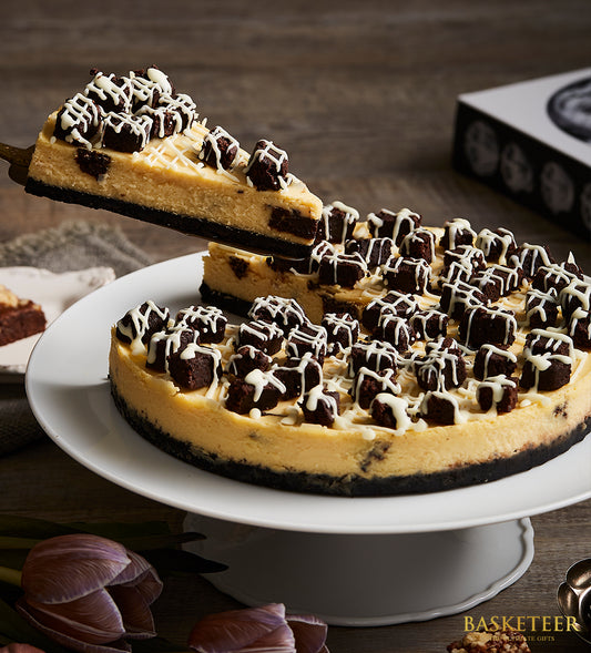 Rich brownie cheesecake with creamy layers and white drizzle, birthday celebration cake on white stand