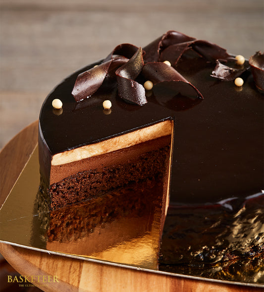Decadent layered chocolate cake with glossy glaze and chocolate curls, artisan birthday gift from Charlotte Bakery