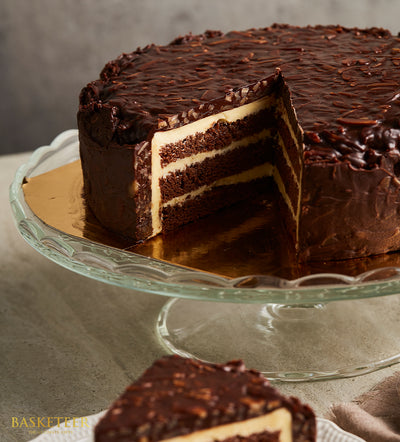 Decadent Swiss chocolate layer cake with ganache and nuts on glass cake stand, birthday celebration dessert