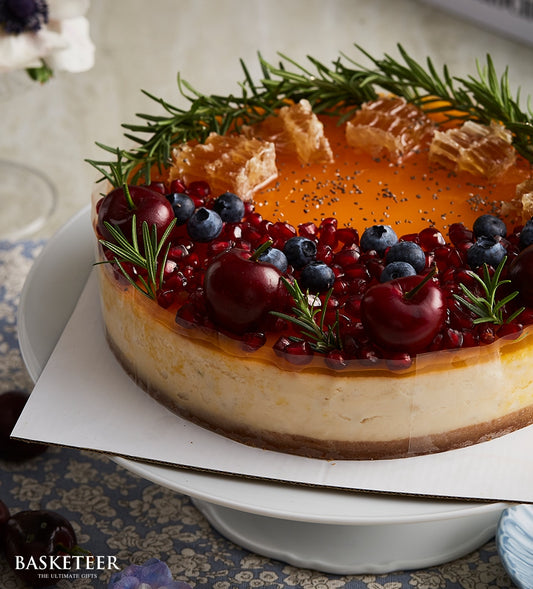Berry Honey Cheesecake with honeycomb, blueberries, and pomegranate on white cake stand