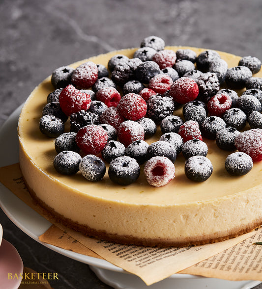 Classic mixed berry cheesecake with fresh raspberries, blueberries, and powdered sugar on graham cracker crust