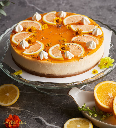 Charlotte Bakery Passion Fruit Cheesecake: Artisan pastry on glass stand, citrus slices, meringue kisses, yellow flowers. Custom cake Bangkok delivery.