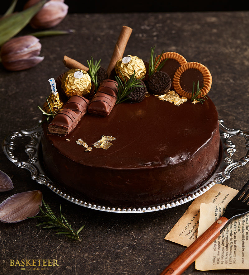 Decadent chocolate cake with Ferrero Rocher, Kinder Bueno, and gold leaf on silver serving tray