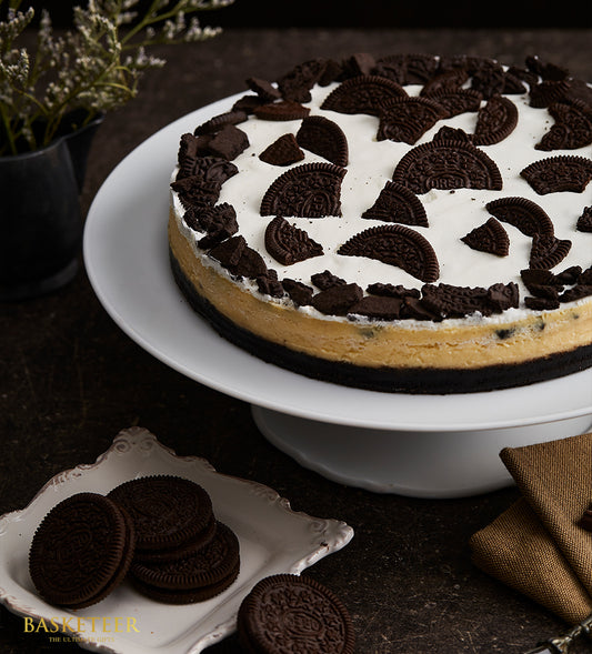 Oreo cheesecake with dark cookie crust, creamy filling, and white cream topping decorated with cookie pieces on ceramic stand