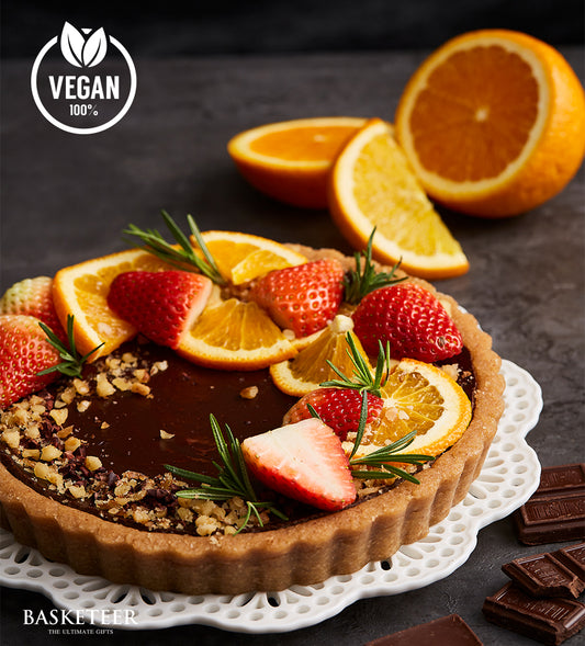 Dark chocolate vegan fruit tart with fresh strawberries, oranges, and rosemary garnish