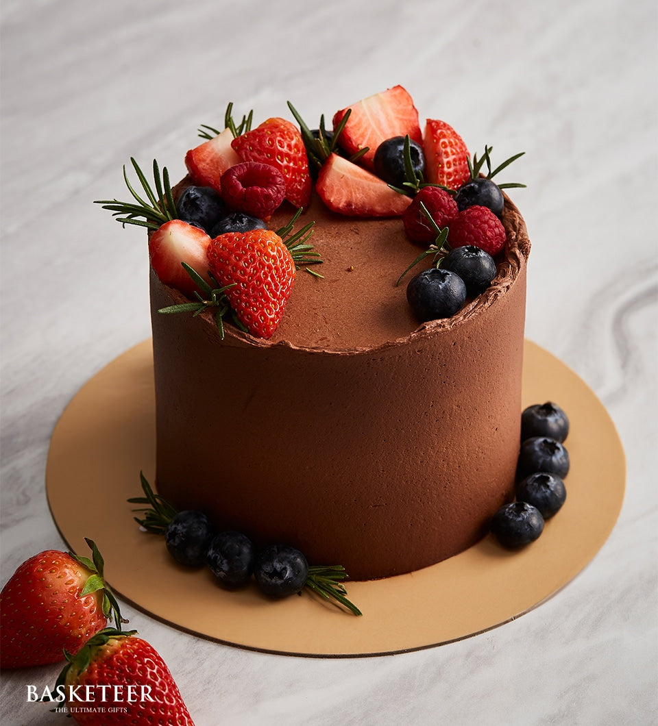 Dark chocolate cake with fresh berries and rosemary on gold board, premium celebration dessert