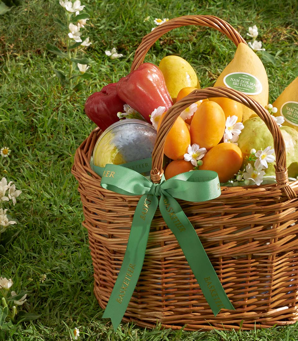 Golden Harvest mango gift basket with premium Thai fruit, woven wicker, green ribbon bow