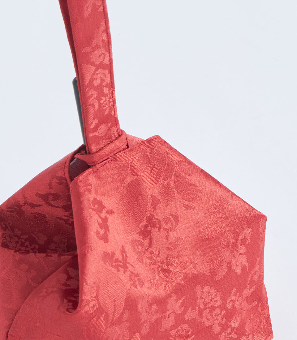 Red brocade gift basket with gathered fabric and dark handle for elegant gifting