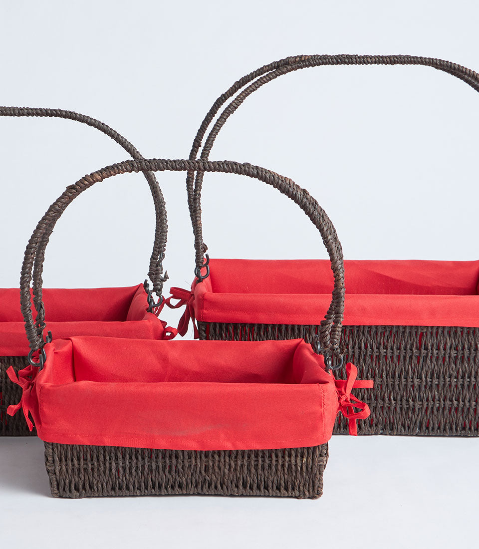 Handwoven wicker baskets with red fabric liners and twisted rope handles, set of three sizes