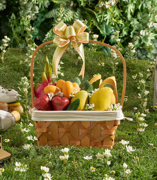 Premium tropical fruit basket with mangoes, papayas, and dragon fruit in woven wood with cream linen