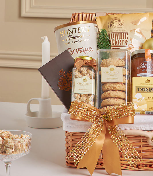 Wicker gift hamper with truffle chips, gourmet cookies, marmalade, and tea tied with gold ribbon for New Year