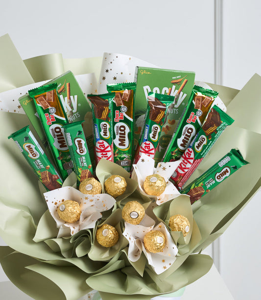 # Alt Text:
Luxury gift bouquet with green and cream wrapping, featuring green Glico snack packages, KitKat bars, and golden Ferrero Rocher chocolates arranged with decorative paper accents.