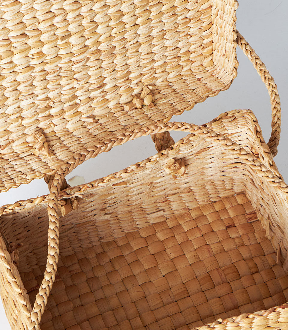 Natural woven straw basket with braided handles and fitted lid for premium gift presentation