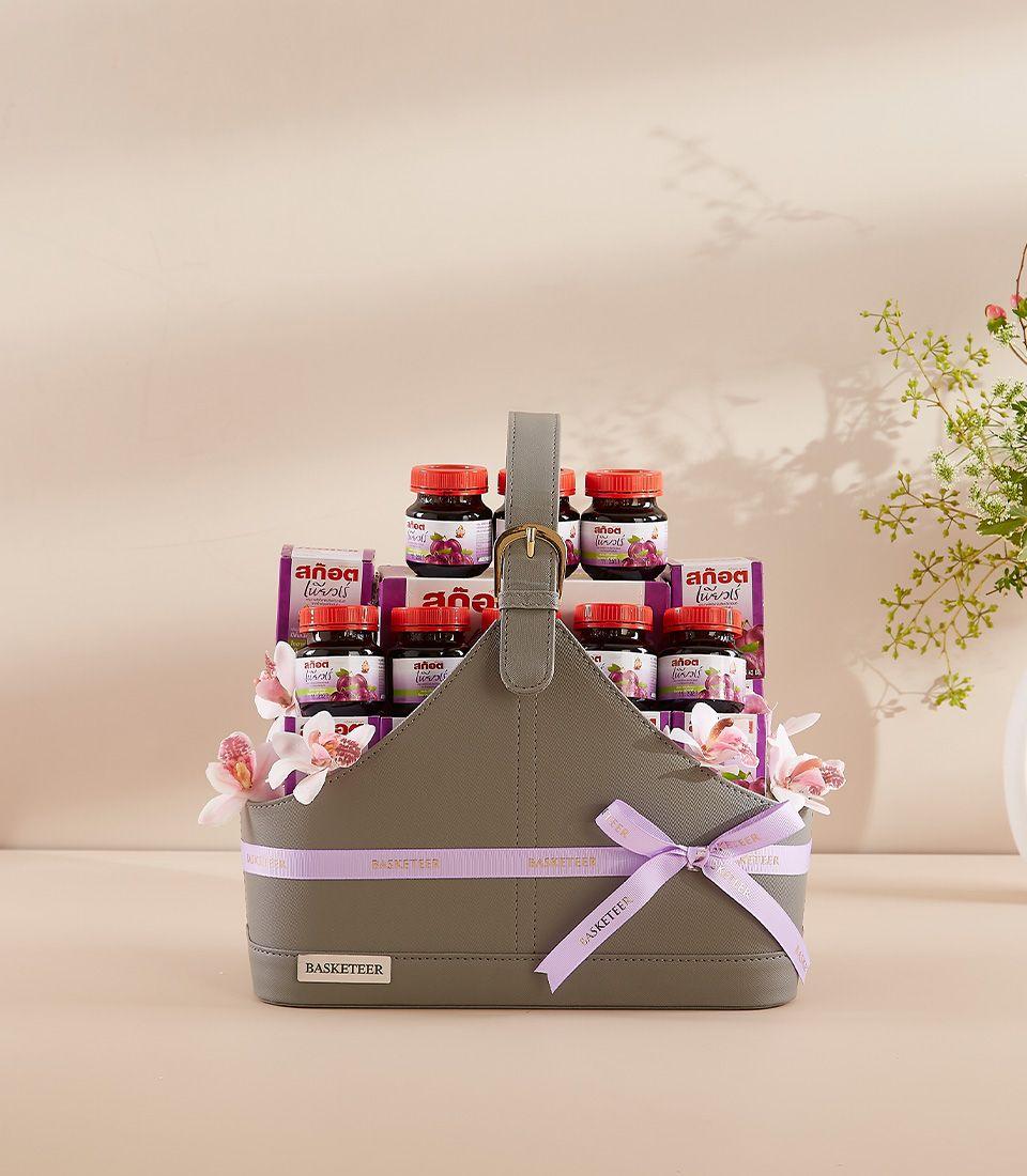 Harmony Scotch Wellness grey leather gift basket with grape preserve jars, purple ribbon, and orchid flowers