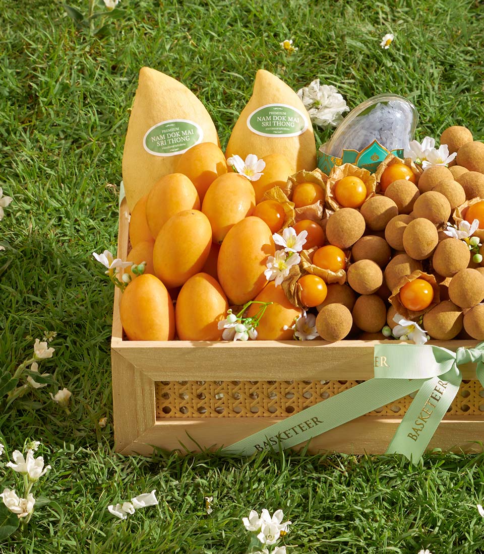 Premium wooden gift box with Nam Dok Mai mangoes, physalis, and longans on green grass background