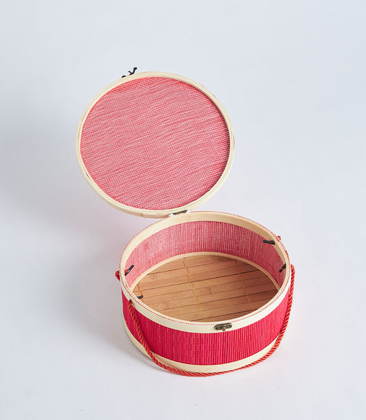 Red round bamboo gift basket with braided handle and two-tier lid, artisan woven design