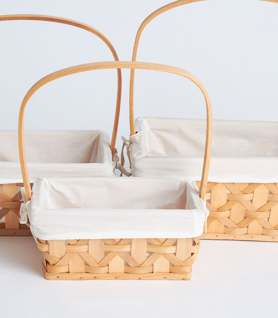 Light natural wicker baskets with tall handles and removable fabric liners, perfect for curated gifts