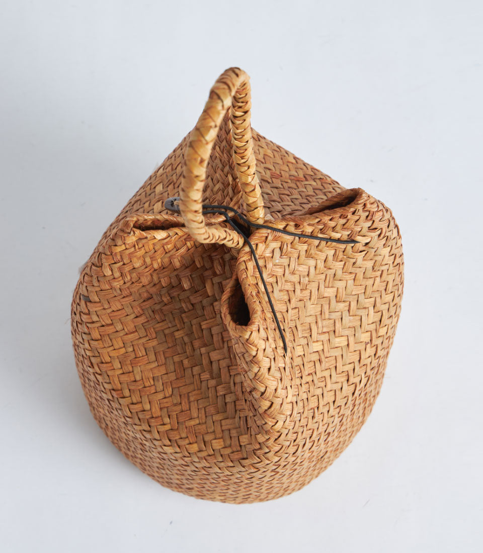 Hand-woven natural straw gift basket with braided rope handle and red tassel