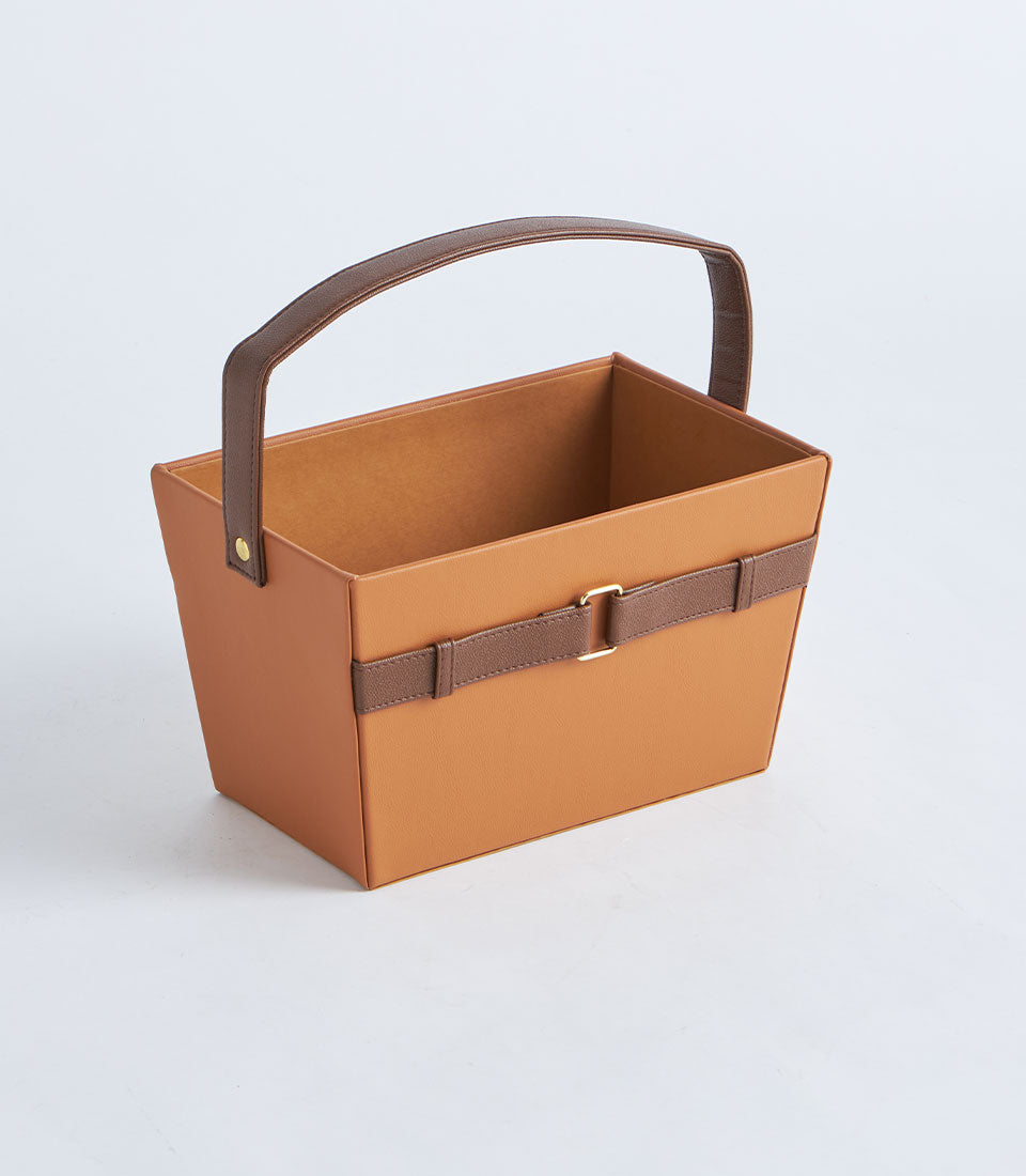 Tan leather gift basket with arched handle and gold buckle strap detail