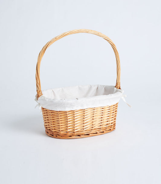 Natural wicker oval basket with white fabric lining and arched handle for gift presentation