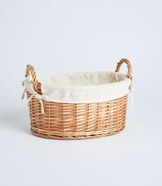 Handwoven oval wicker basket with cream fabric lining and twisted handles