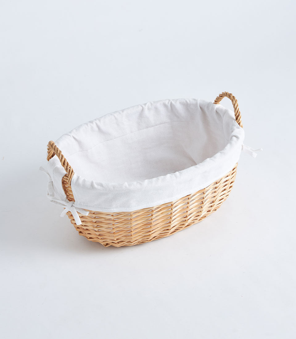 Large natural wicker oval basket with white linen lining and braided handles