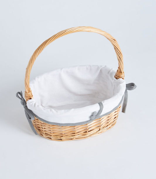 Handwoven oval wicker basket with arched handle and white fabric lining, ready for custom gift filling