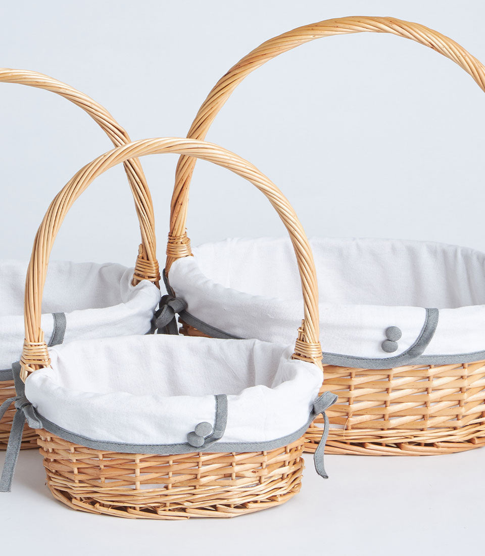 Handwoven wicker baskets with white fabric liners and grey trim in three sizes