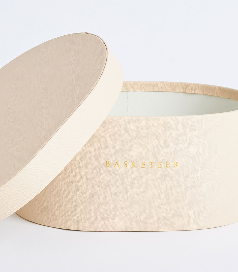 Beige round leather storage box with textured lid and cream linen interior, luxury gift packaging