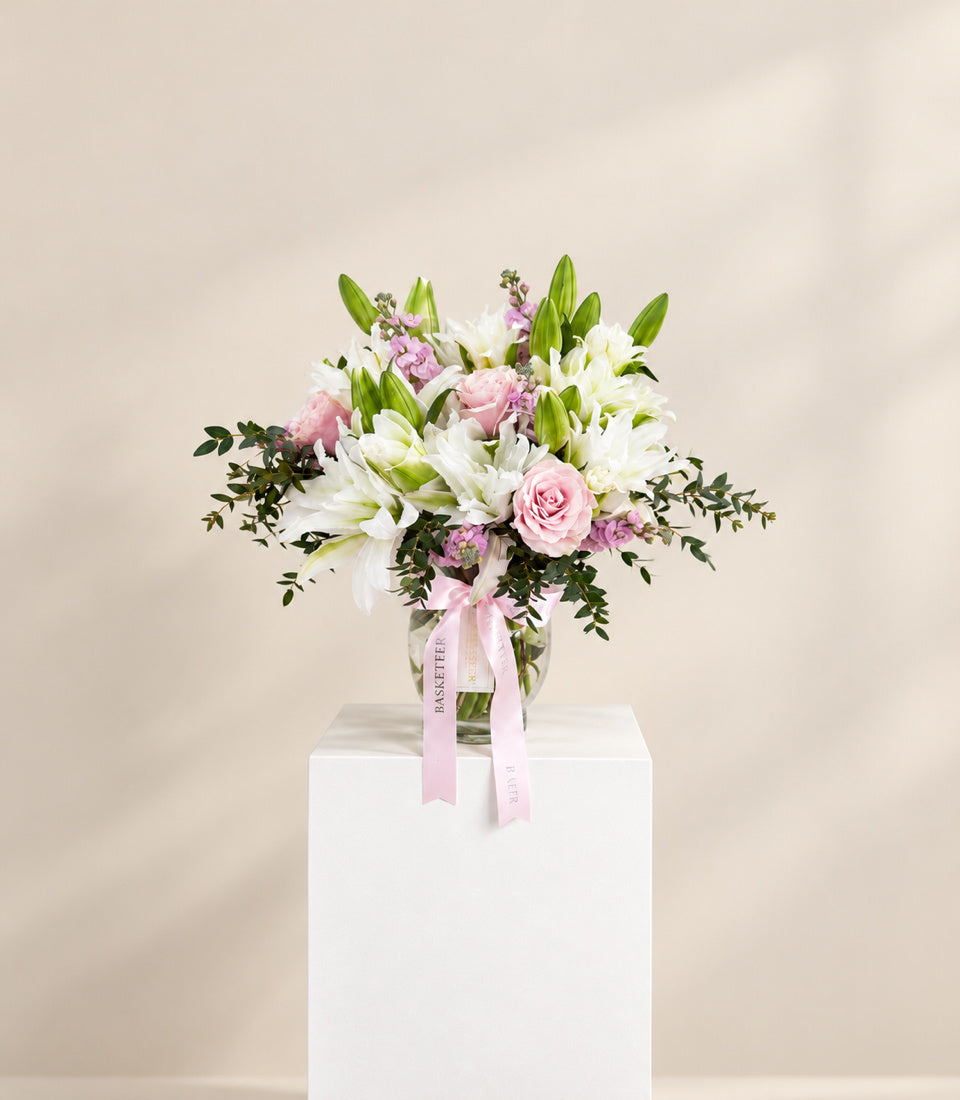 Wide studio view of Roselily Blush pink and white flower arrangement in a clear glass vase