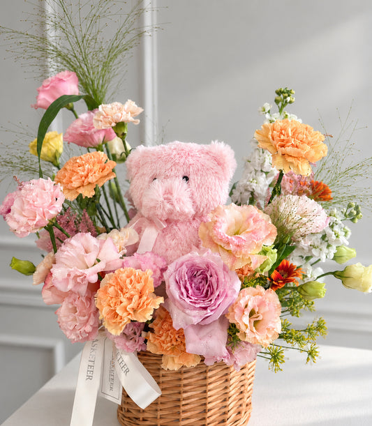 A romantic flower basket with a plush pink teddy bear nestled among premium pink O