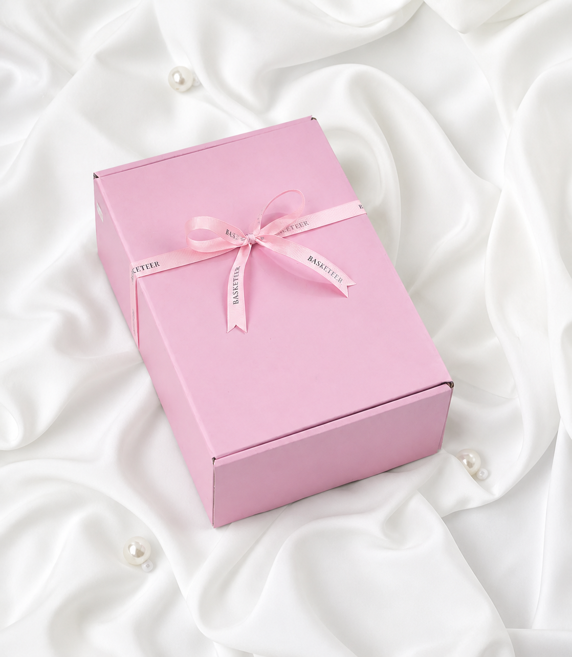 A luxurious Basketeer pink gift box tied with a branded satin ribbon bow, presented